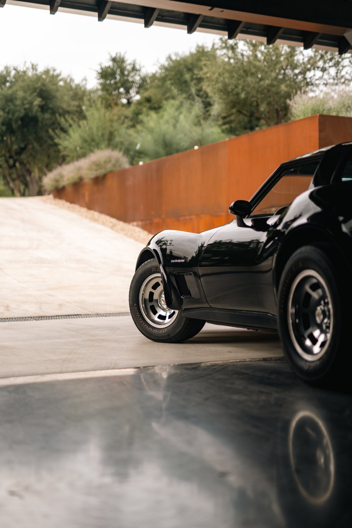 Black 1982 Chevrolet Corvette Stingray with classic rims, parked in a garage.