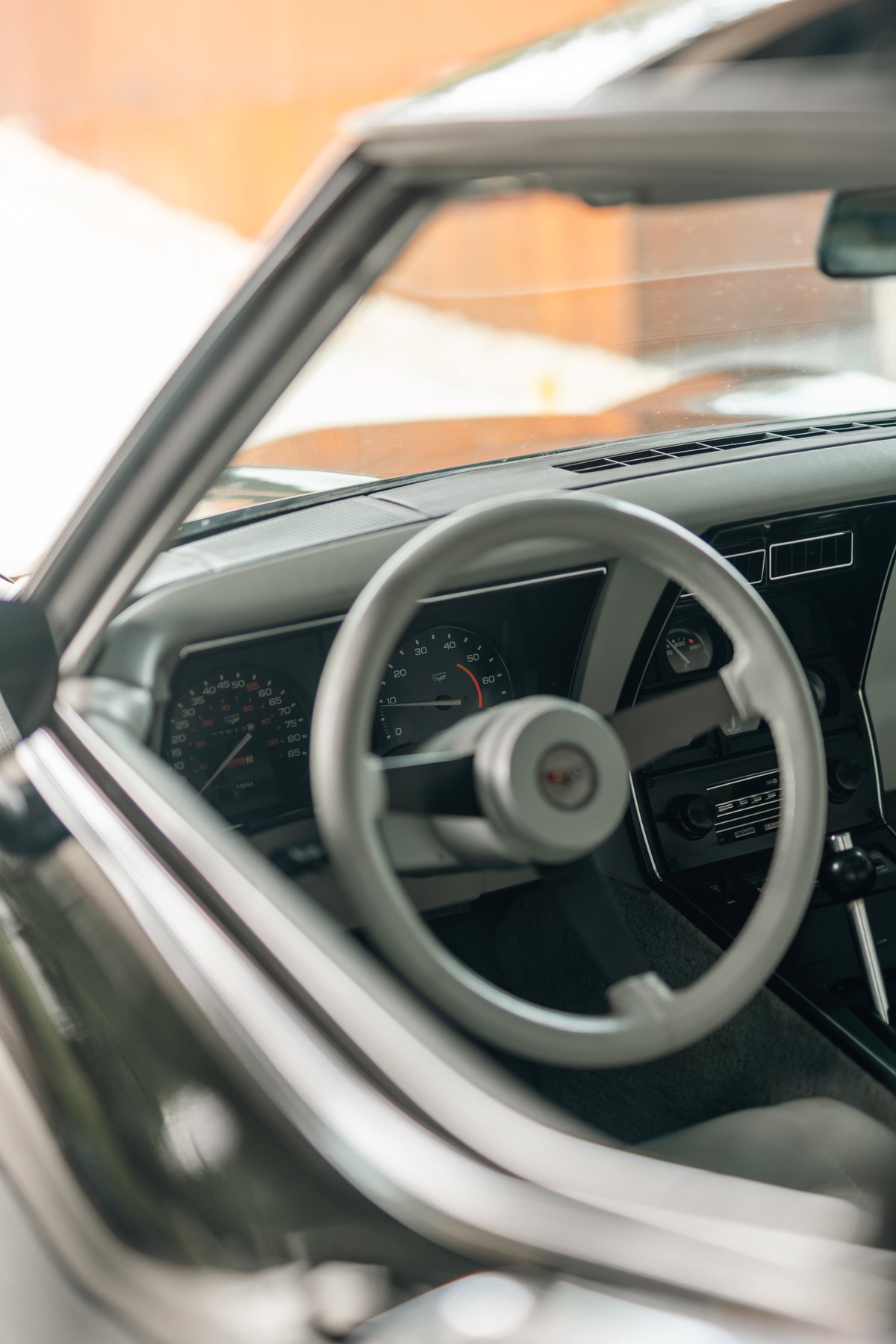 1982 Chevrolet Corvette Stingray interior. Close-up of the beige steering wheel, dashboard, and gauges.