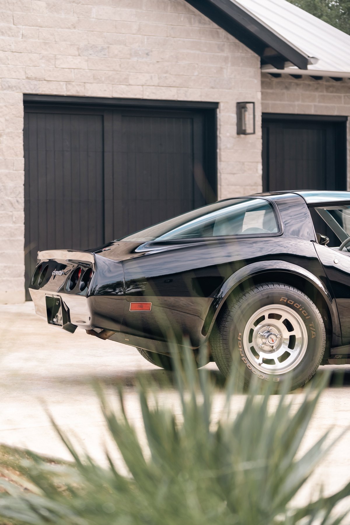 Rear three-quarter view of a black 1982 Chevrolet Corvette Stingray with chrome trim and a factory aluminum rim.