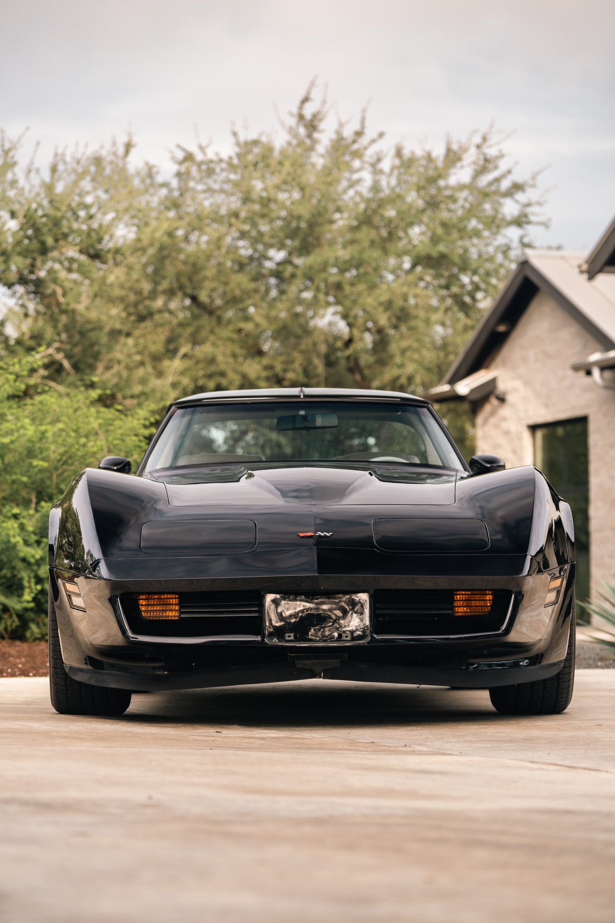 Front view of a black 1982 Chevrolet Corvette Stingray with orange turn signals and a license plate.
