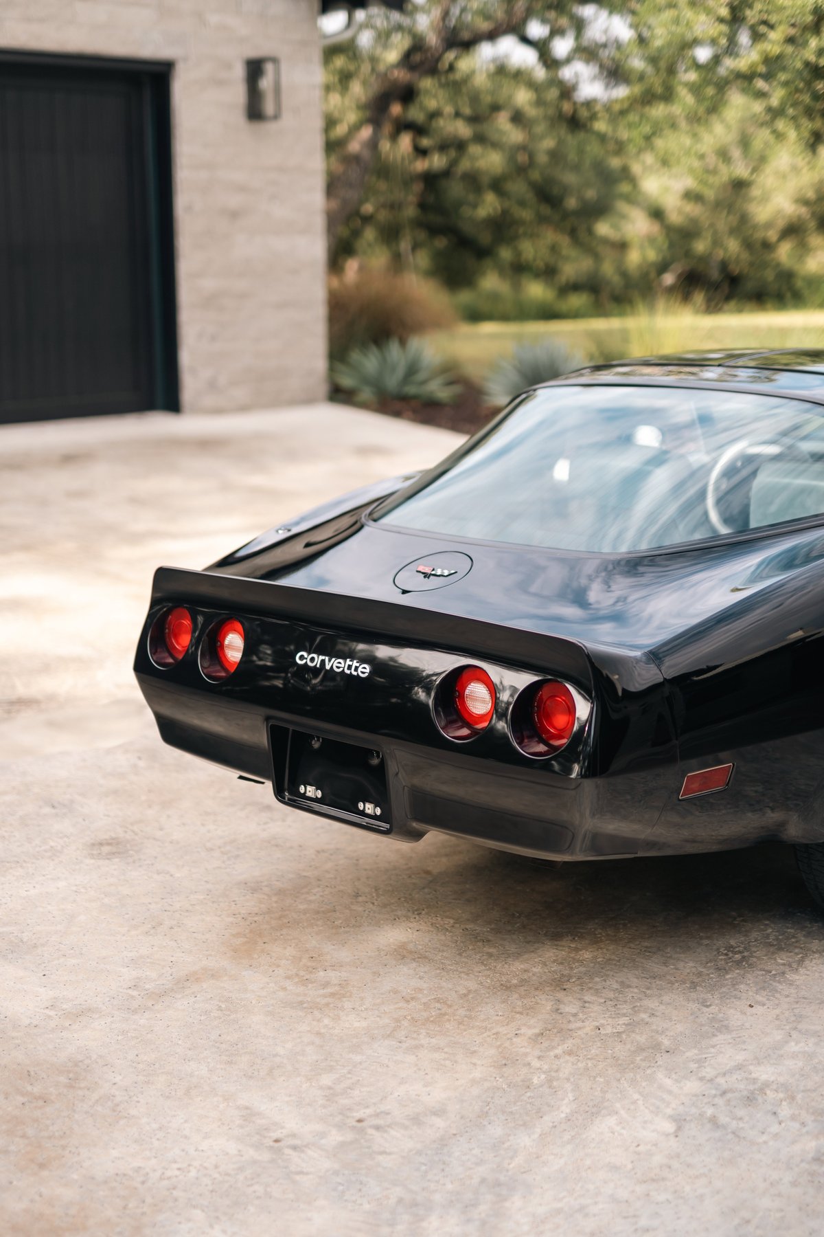 Rear view of a black 1982 Chevrolet Corvette Stingray with quad taillights and a ducktail spoiler.