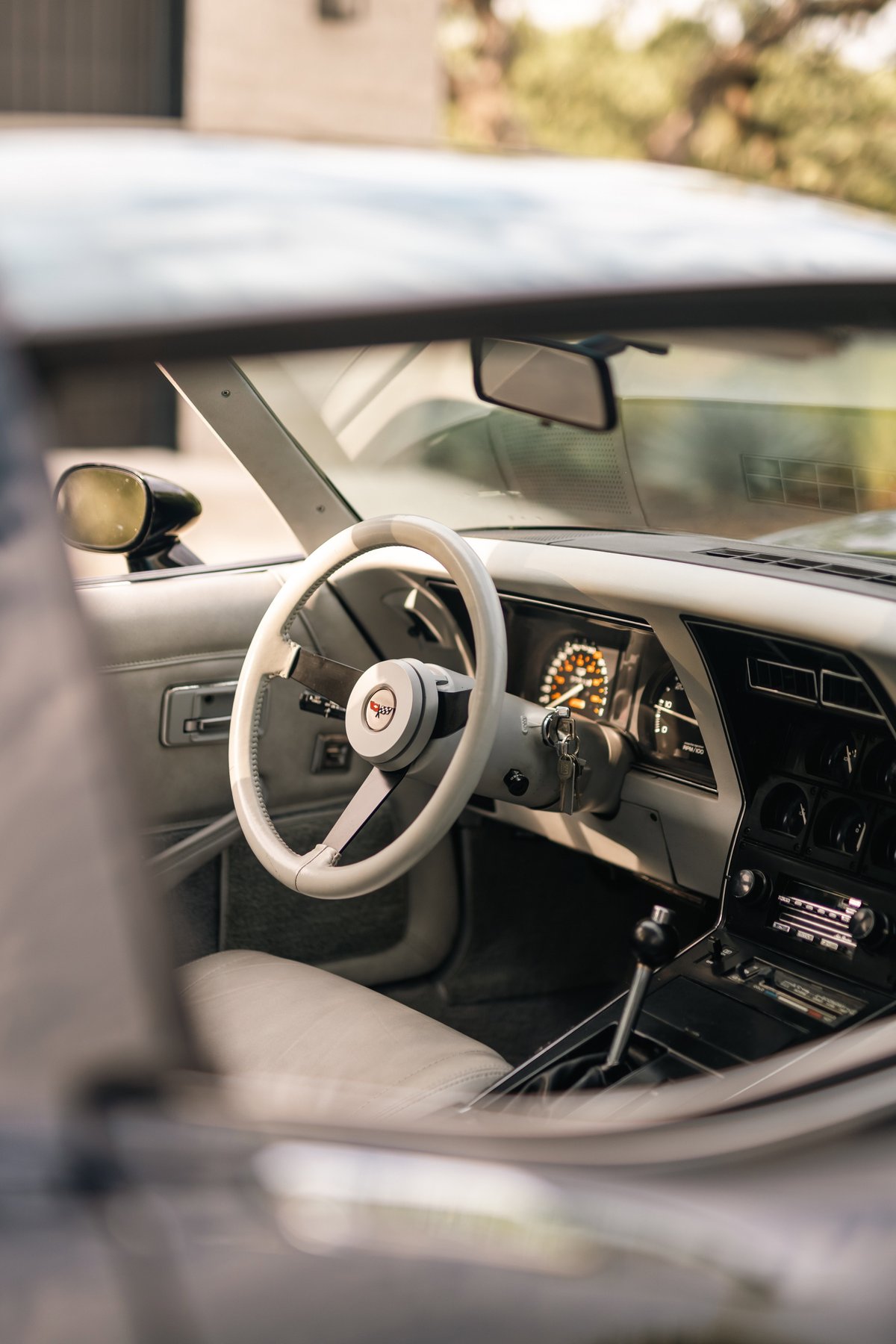 Interior of a 1982 Chevrolet Corvette Stingray. Beige leather seats, steering wheel, and dash trim.