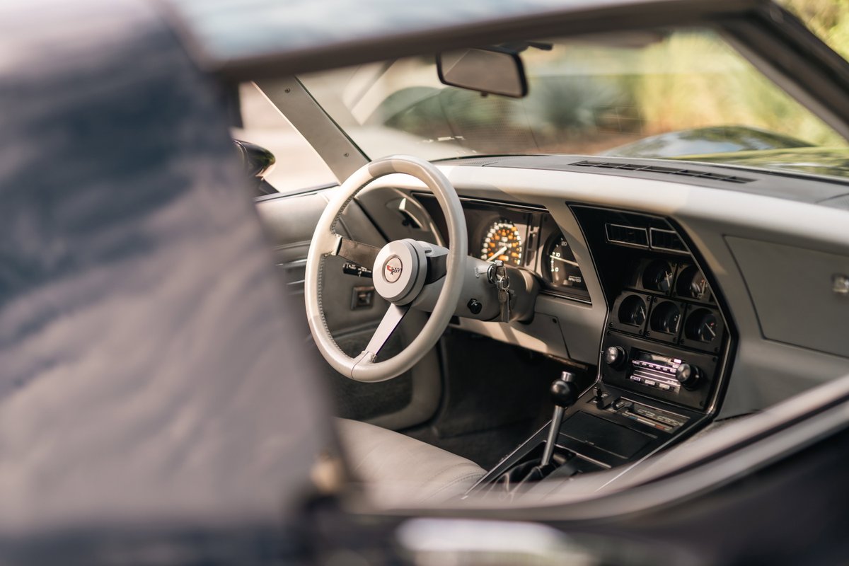 1982 Chevrolet Corvette Stingray interior, showing white steering wheel, dash, and center console.