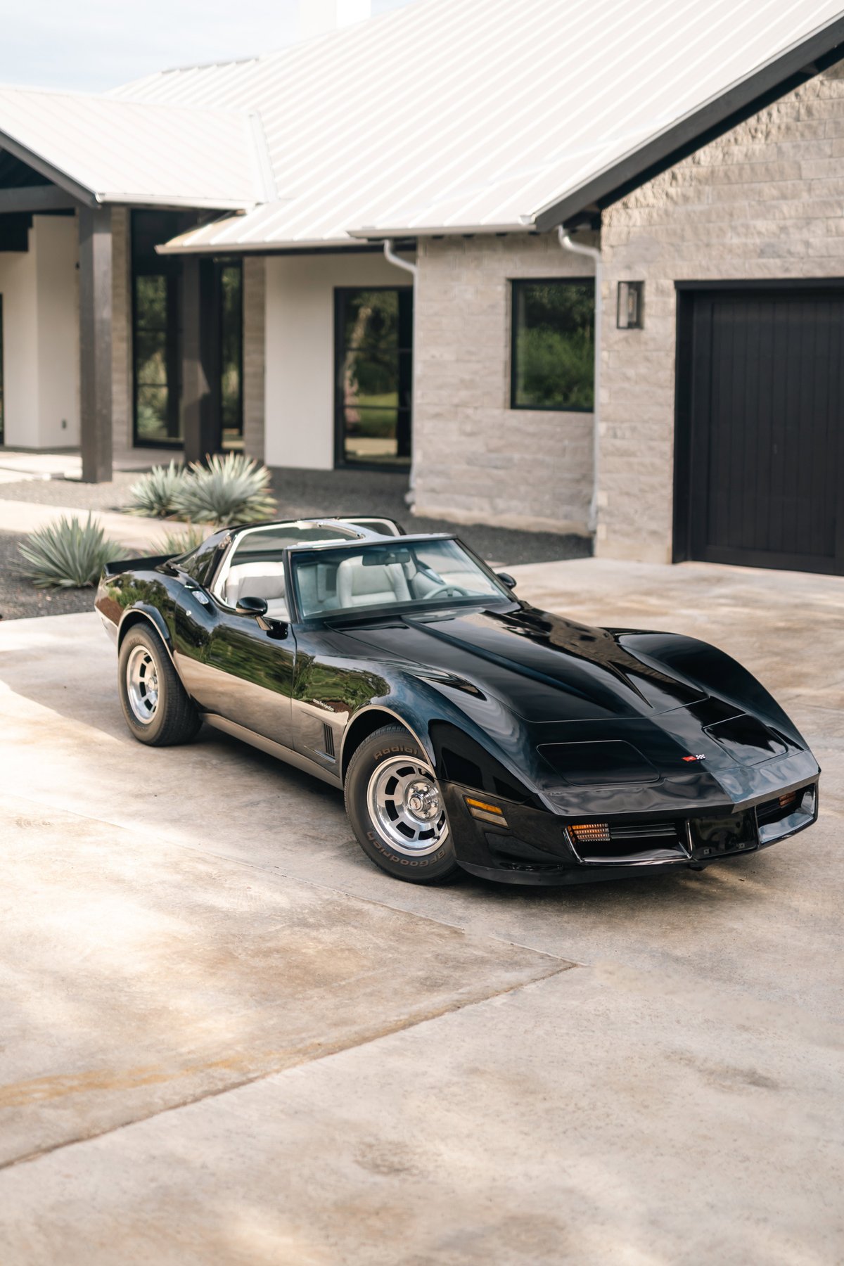 Black 1982 Chevrolet Corvette Stingray T-top with silver rims parked on concrete.