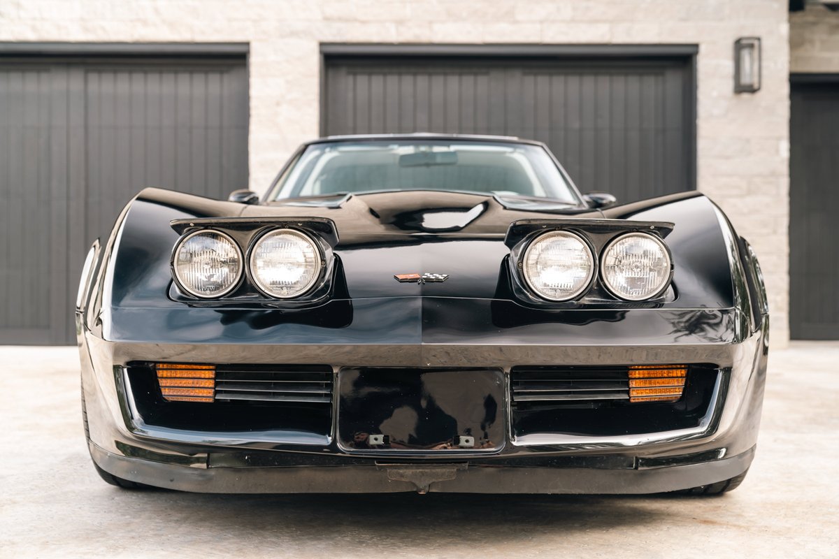 Front view of a black 1982 Corvette Stingray, featuring pop-up headlights and amber turn signals.