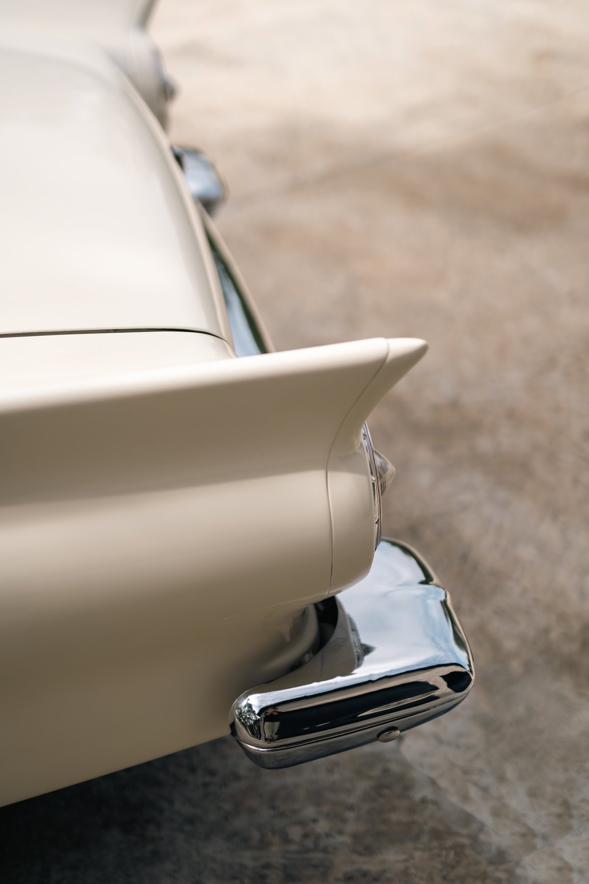 1957 Ford Thunderbird rear end, showing the iconic tail fin and chrome bumper. Colonial White finish.