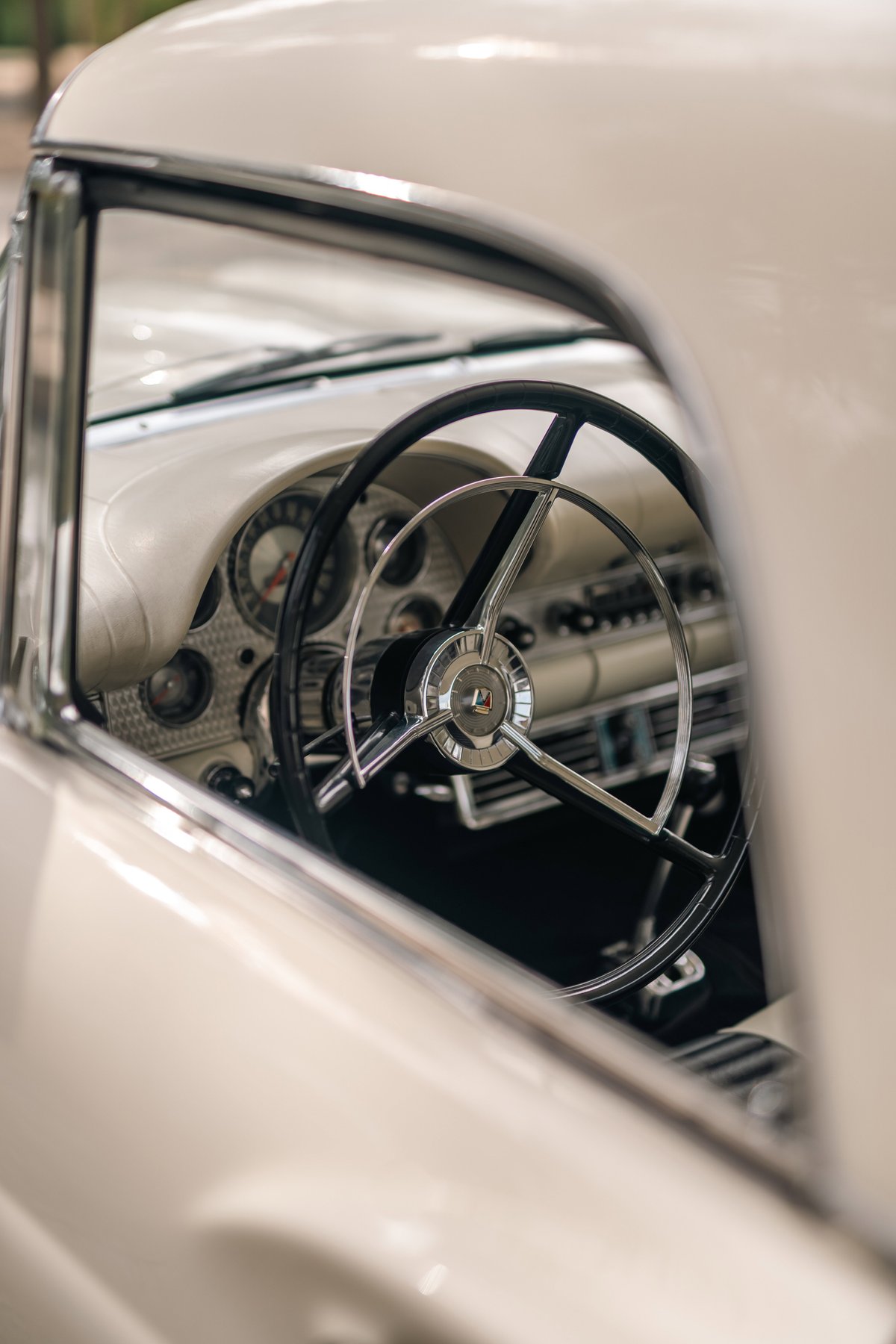 1957 Ford Thunderbird interior, showing the steering wheel and dashboard in colonial white.