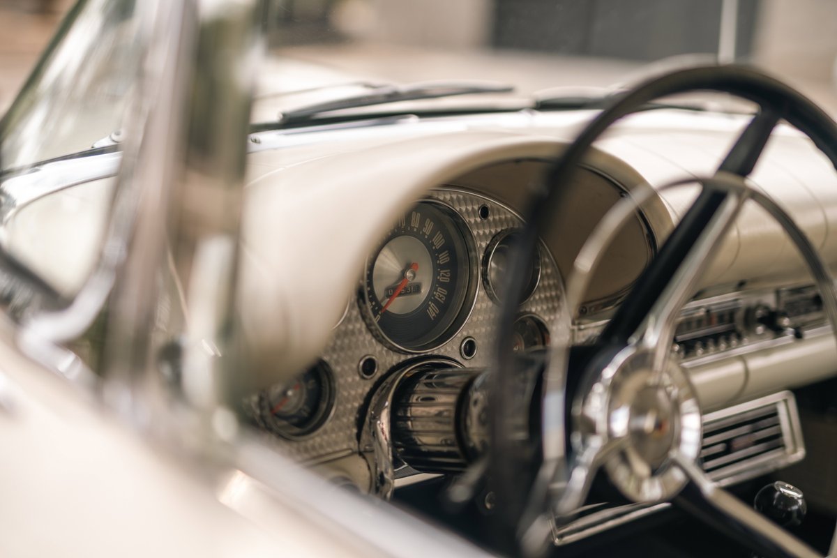 Close-up of a 1957 Ford Thunderbird dashboard, featuring a vintage steering wheel and chrome trim.