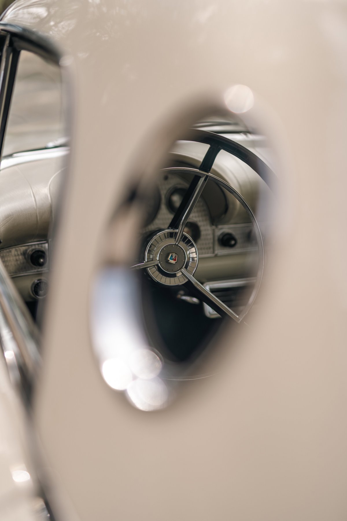 Close-up interior shot of a white 1957 Ford Thunderbird's steering wheel and dashboard.