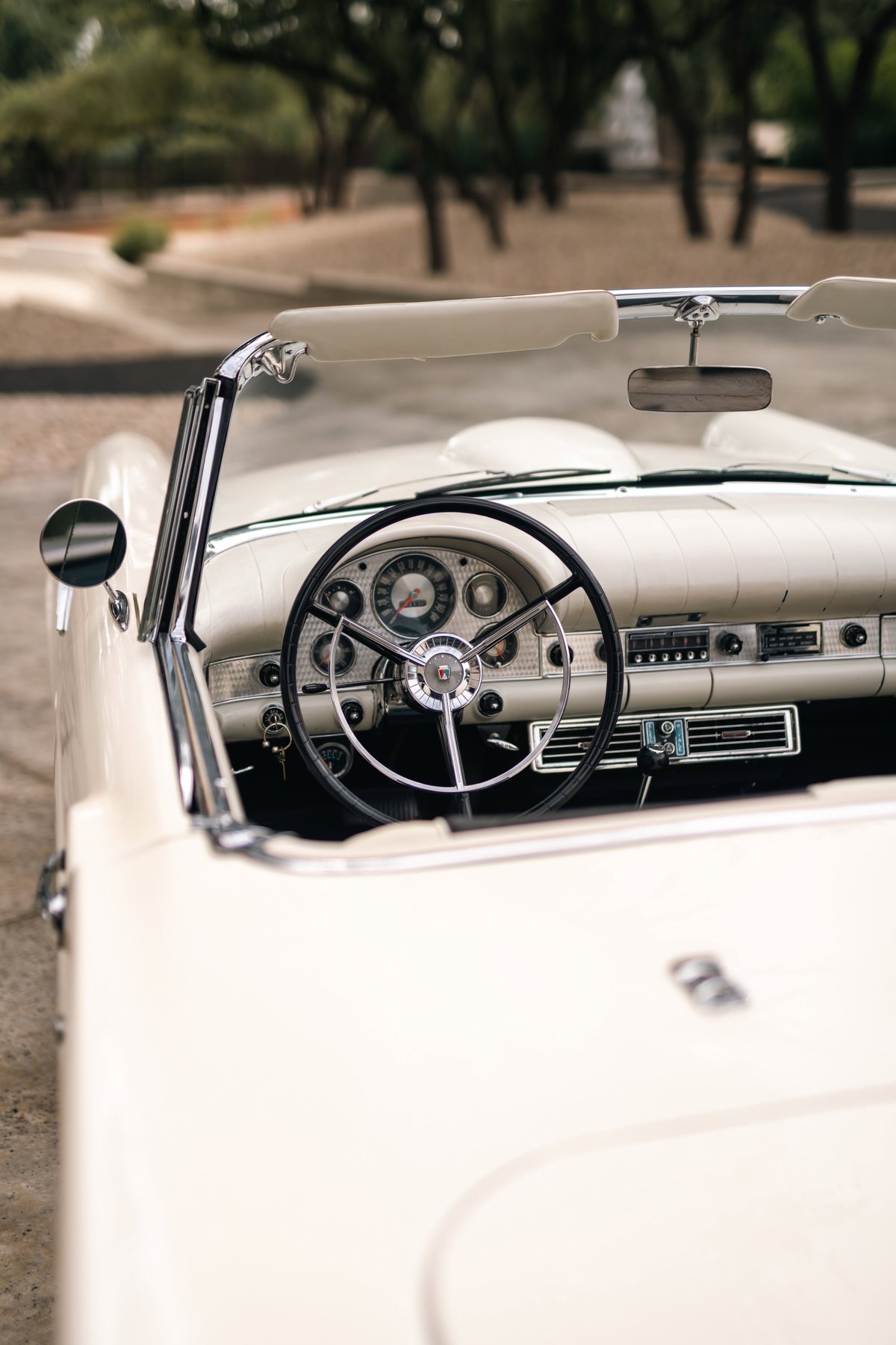 Interior of a colonial white 1957 Ford Thunderbird convertible, showing the dashboard and steering wheel.