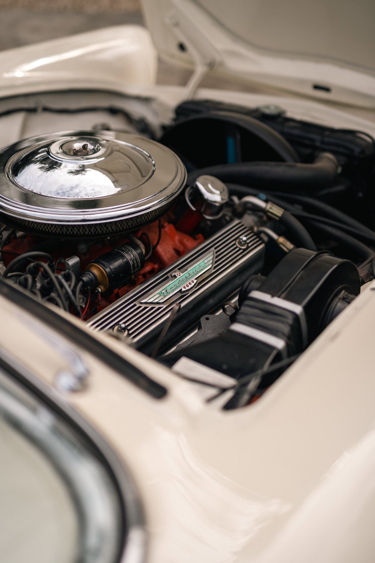 Close-up of a 1957 Ford Thunderbird engine with chrome air cleaner and finned valve covers.