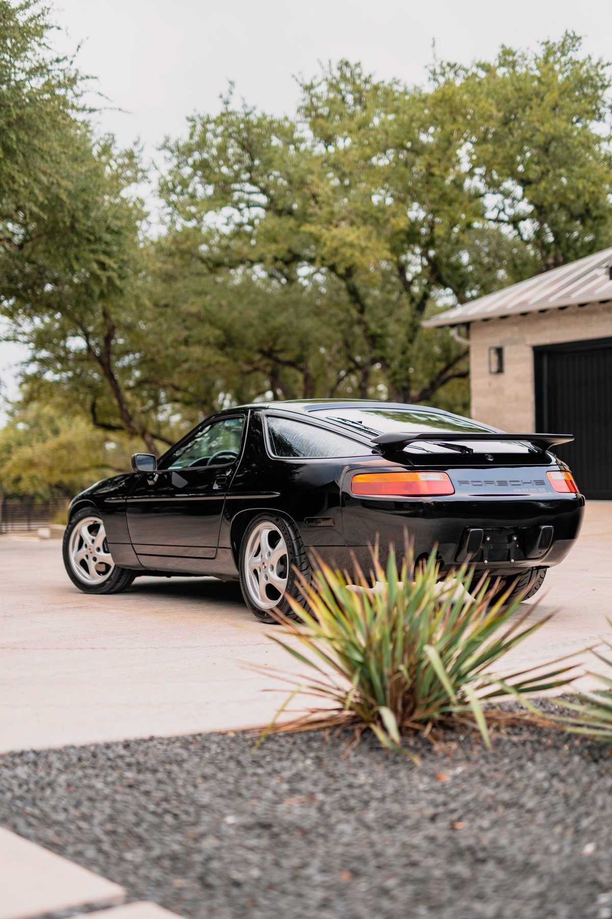 Black 1984 Porsche 928 S4 with turbo-look rims and rear spoiler.