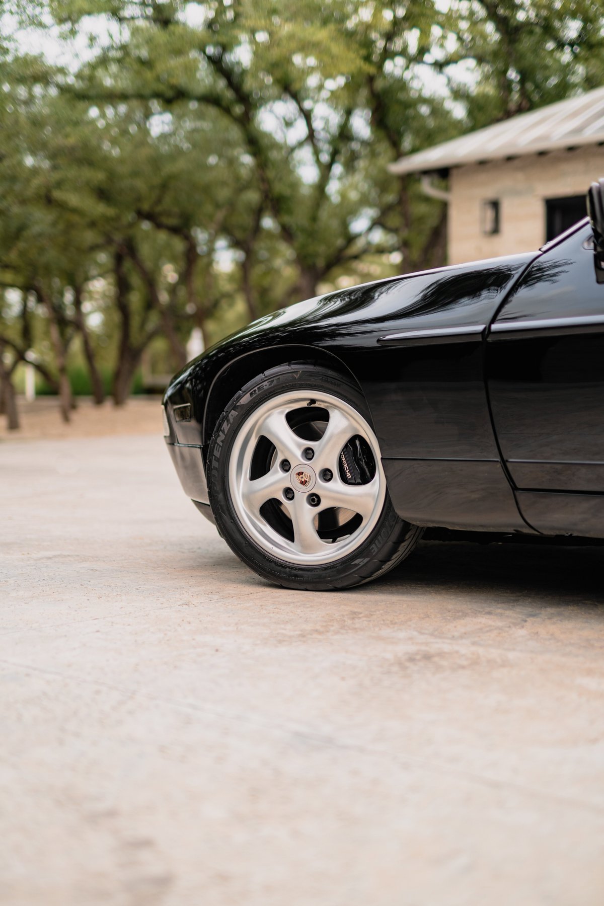 Close-up of a black 1984 Porsche 928 S4 front wheel with silver alloy rims.