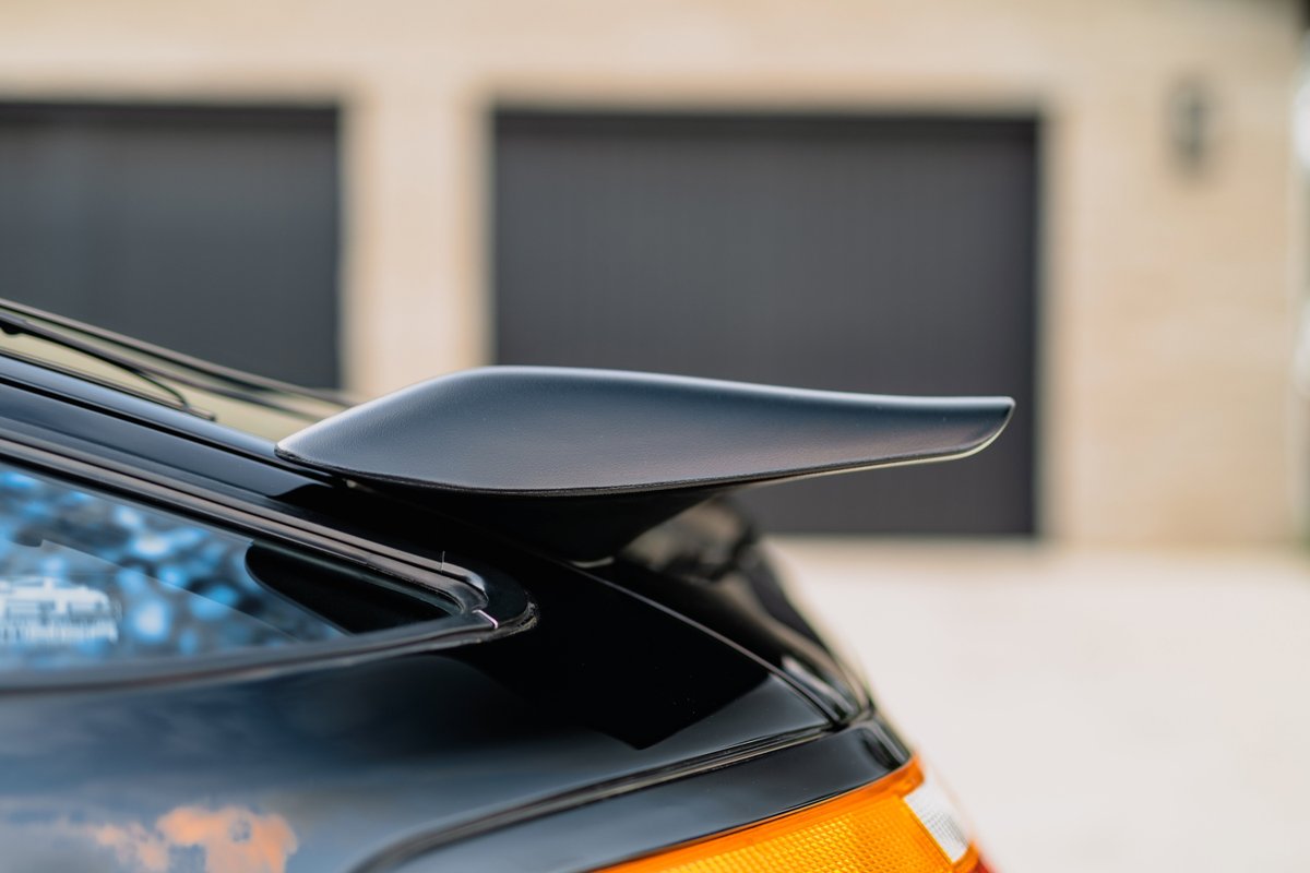 Close-up of a black 1984 Porsche 928 S4 rear spoiler.
