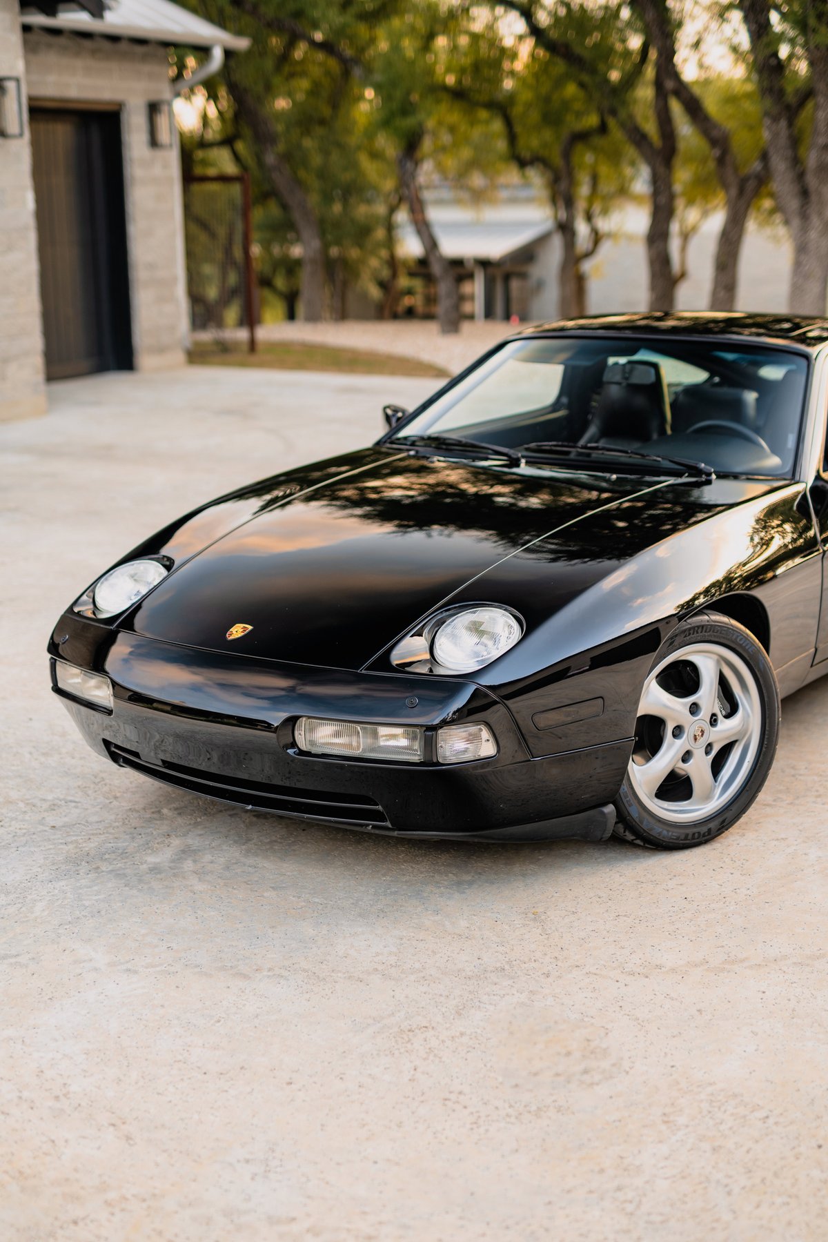 Black 1984 Porsche 928 S4 coupe front quarter view with silver alloy rims.