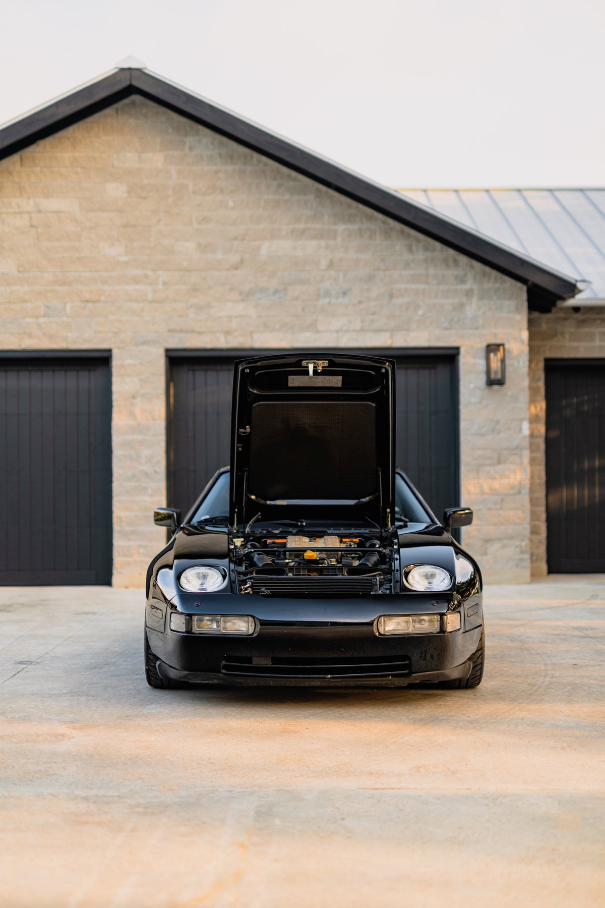 Black 1984 Porsche 928 S4 with hood open, revealing the engine bay.