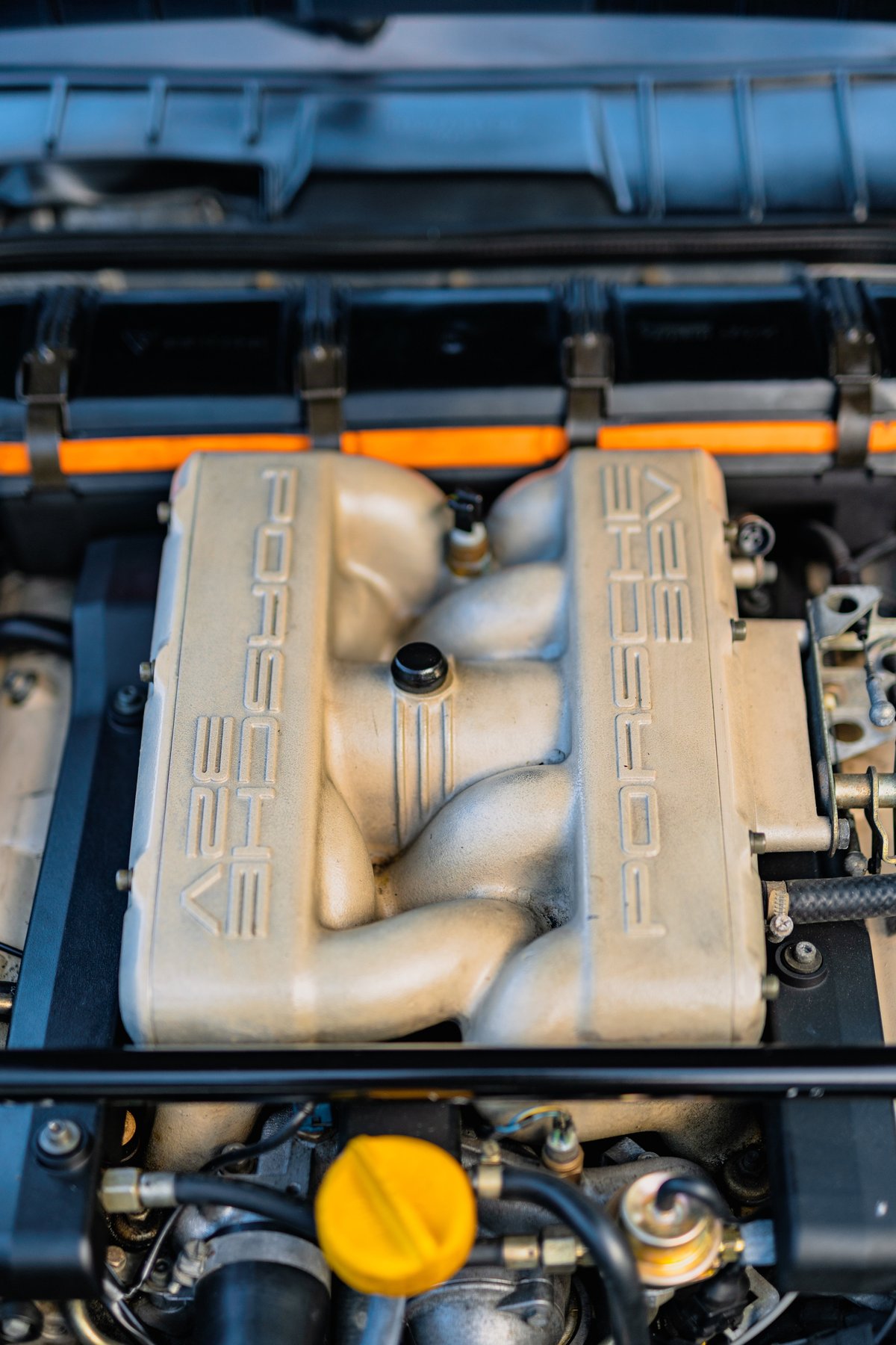 Close-up of a 1984 Porsche 928 S4 V8 engine, showing the intake manifold with "PORSCHE" branding.