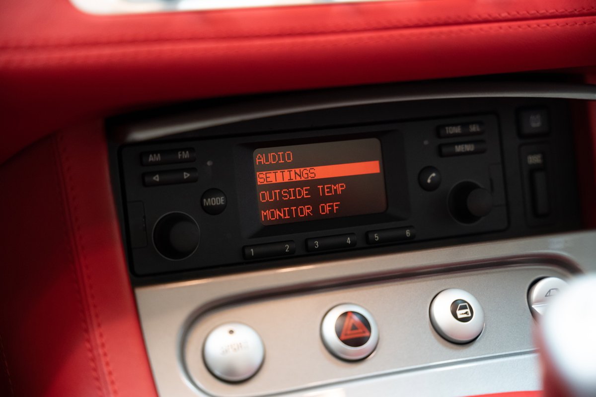 Close-up of a 2002 BMW Z8's red leather interior with its radio display showing "SETTINGS".