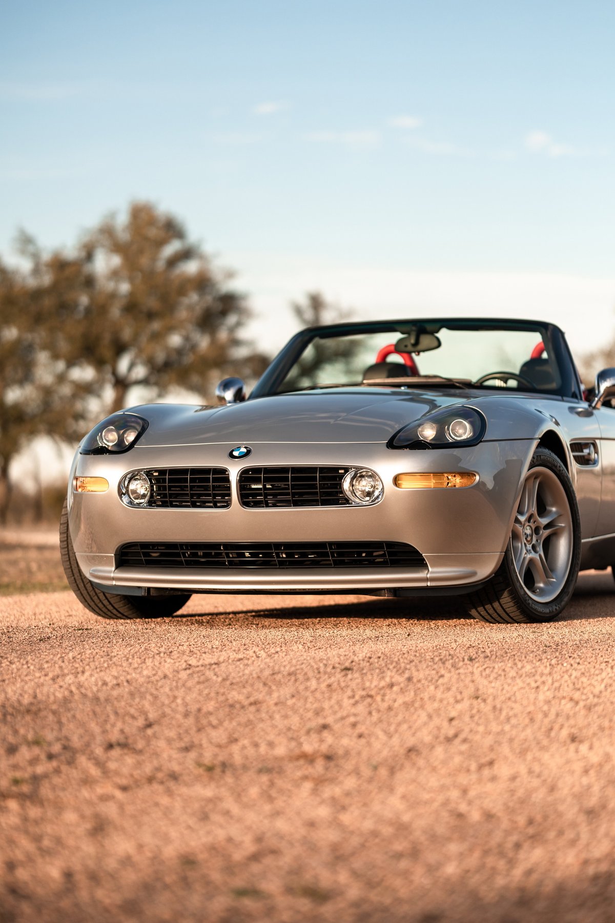 Silver 2002 BMW Z8 roadster with five-spoke rims and red interior trim.