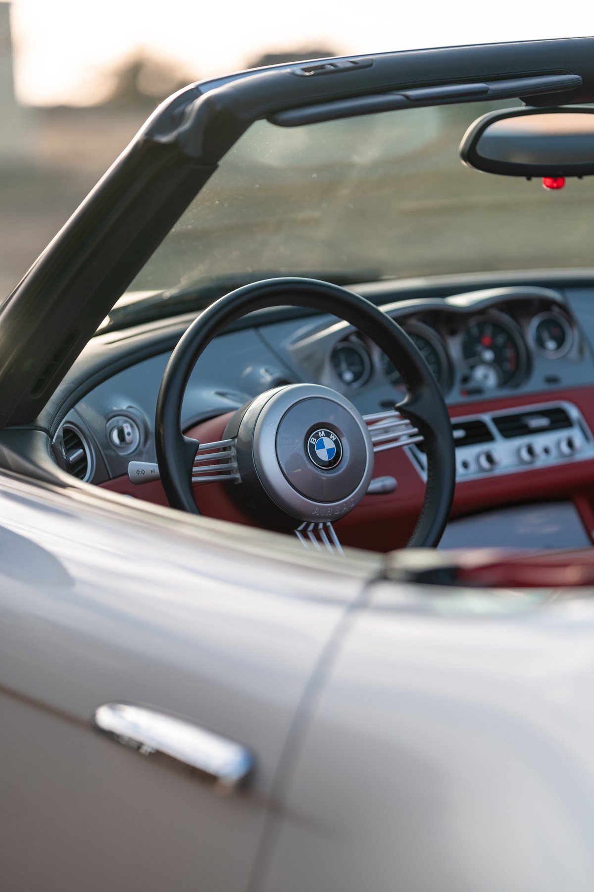 2002 BMW Z8 convertible interior with red leather trim and silver steering wheel.