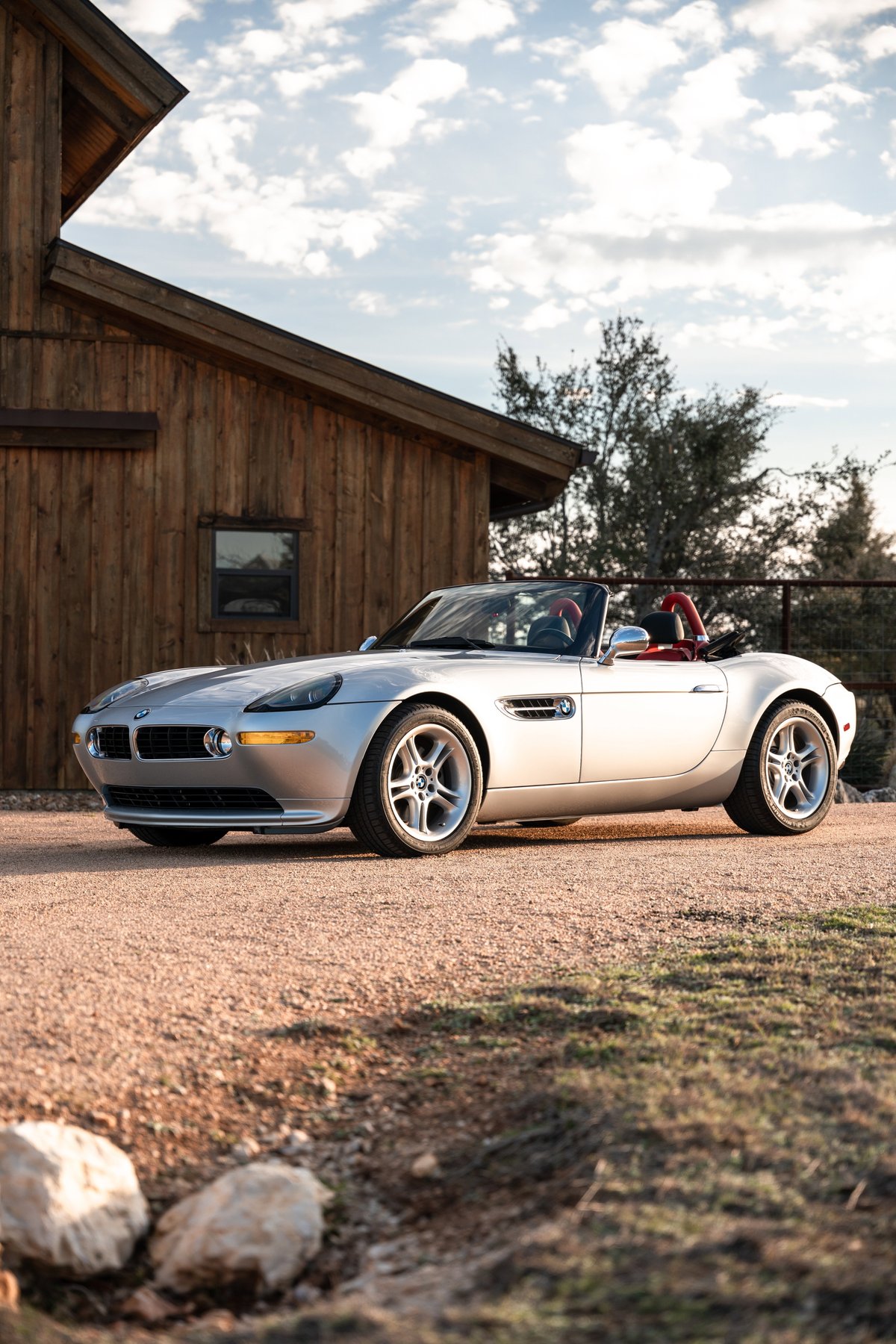 2002 BMW Z8 convertible in Titanium Silver with red interior and multi-spoke rims.