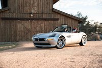 Silver 2002 BMW Z8 roadster with red interior, parked outside a rustic barn.