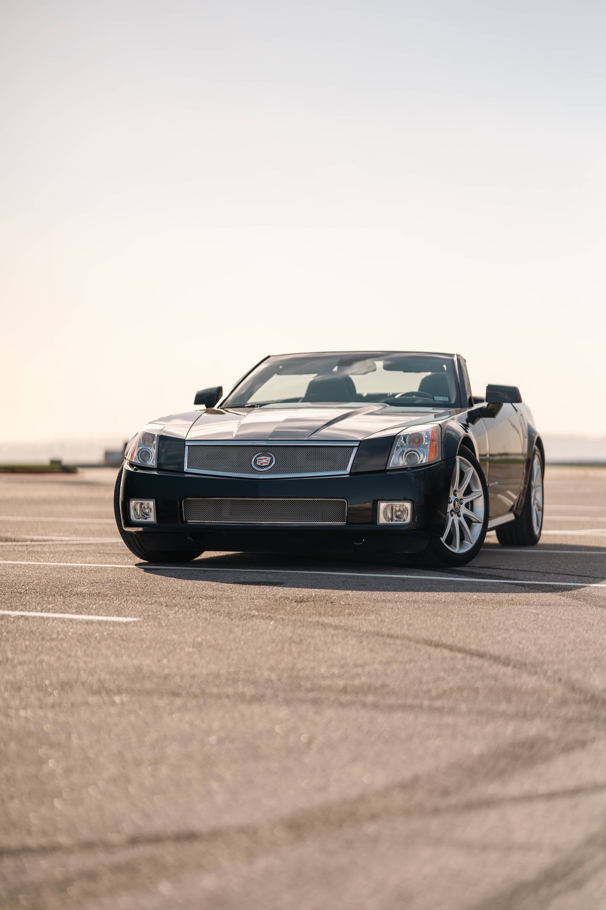 Black 2006 Cadillac XLR-V convertible with chrome trim and multi-spoke rims parked on asphalt.