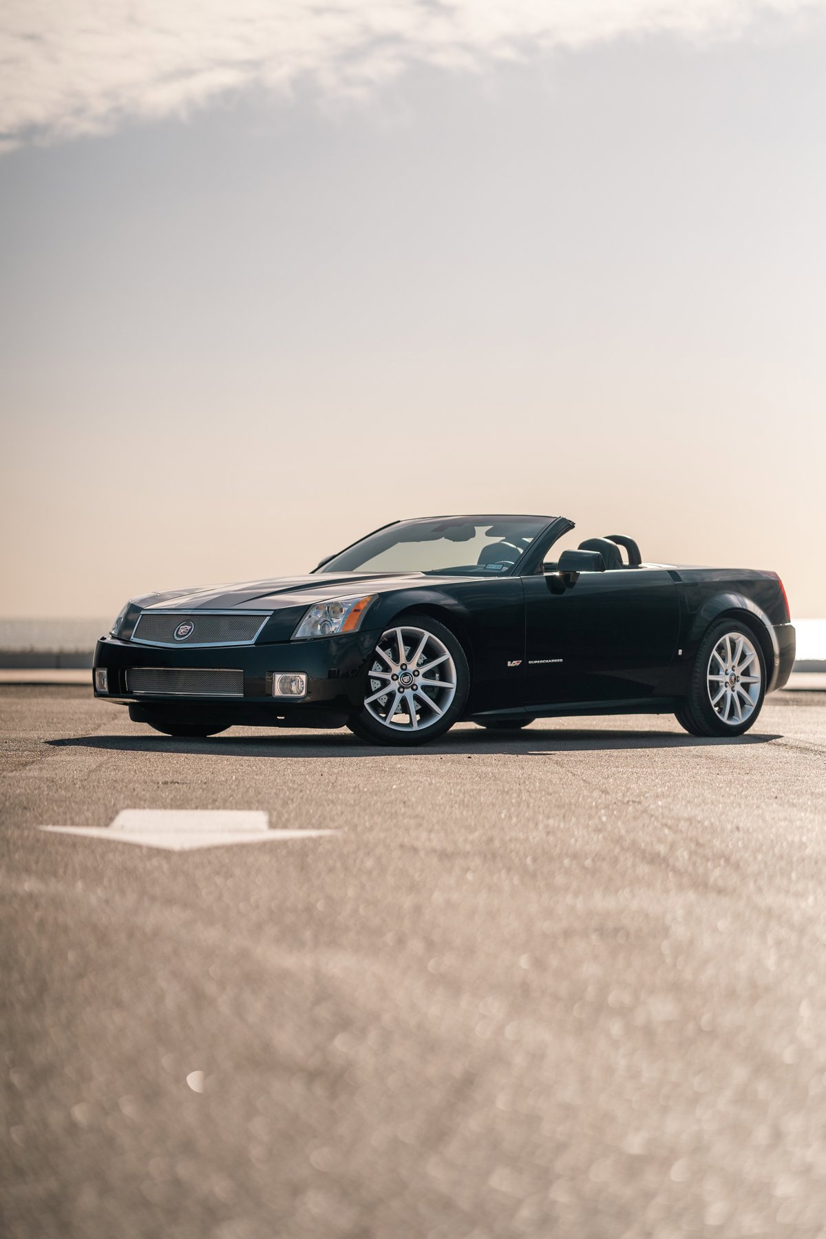 Black 2006 Cadillac XLR-V convertible with chrome rims, parked outdoors on asphalt.