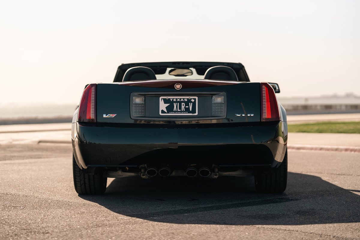 Rear view of a black 2006 Cadillac XLR-V with quad exhaust tips and Texas plates.