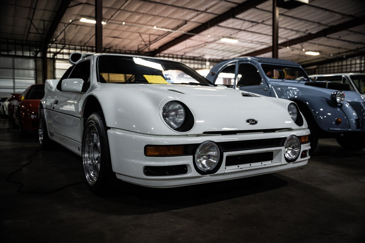 White Ford RS200 with chrome rims in a garage.