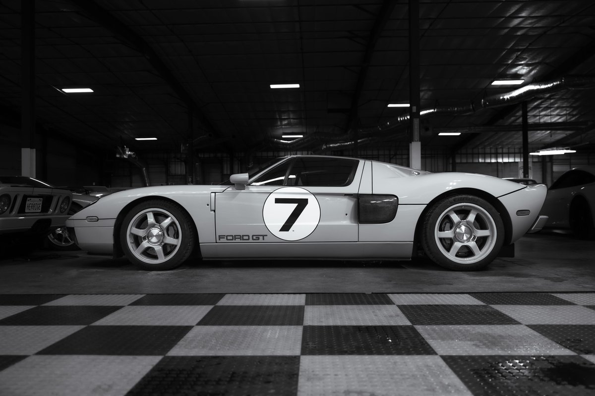 A white Ford GT with race number 7 livery, showcasing its classic lines and alloy rims.