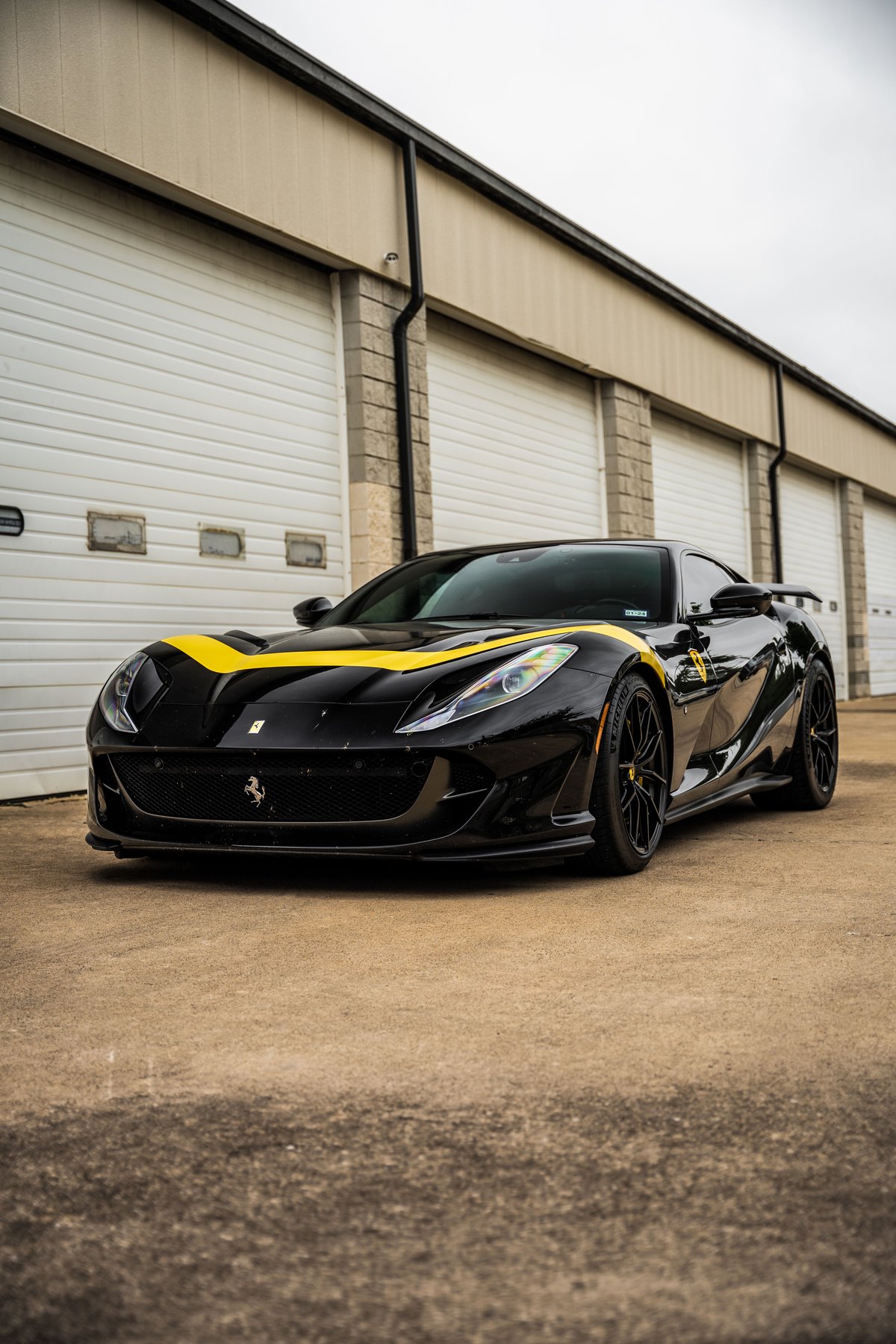 Black Ferrari 812 Superfast with yellow racing stripe livery and black rims.