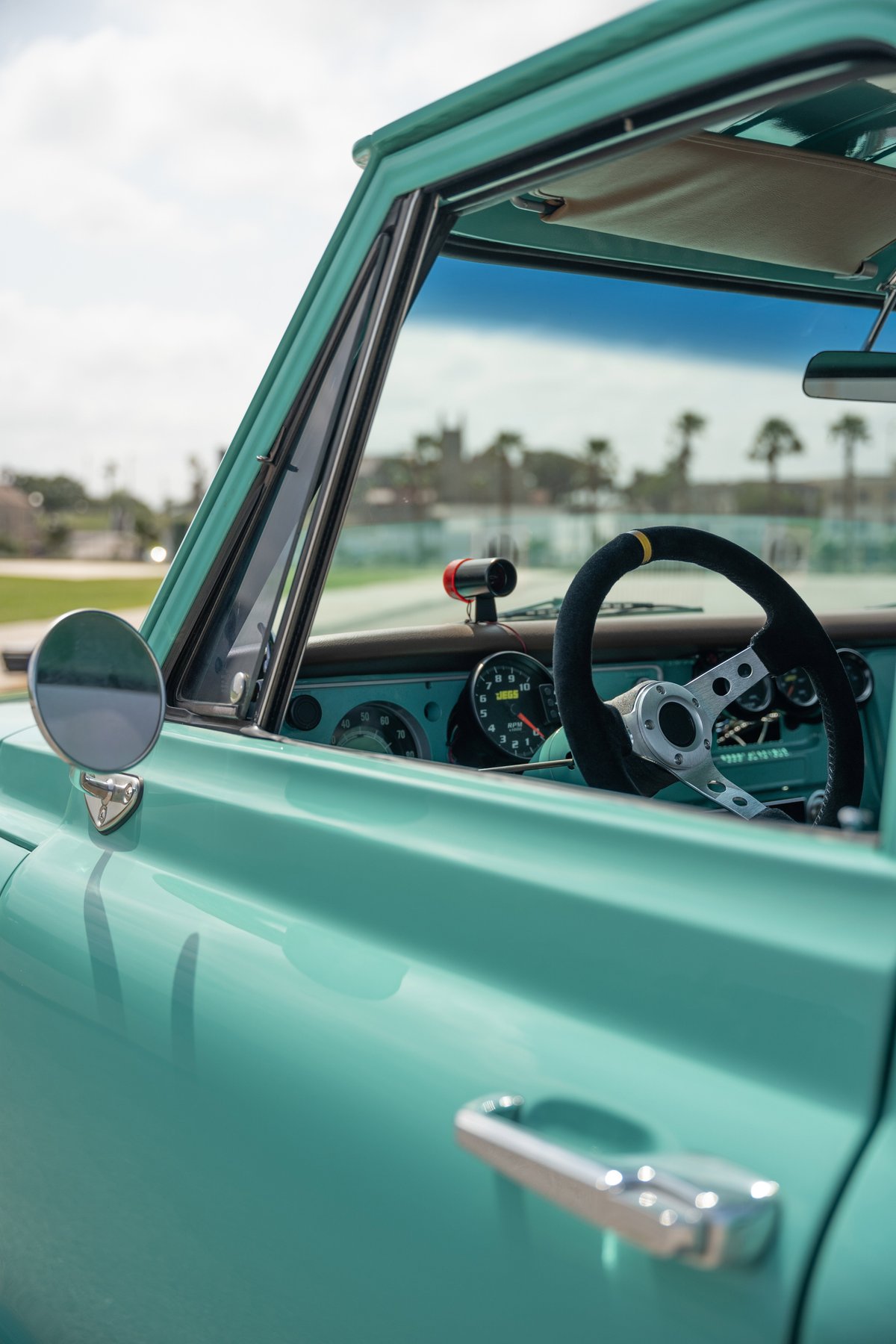 Interior view of a teal 1968 Chevrolet C10 Pro-Street with a black steering wheel and custom dash.