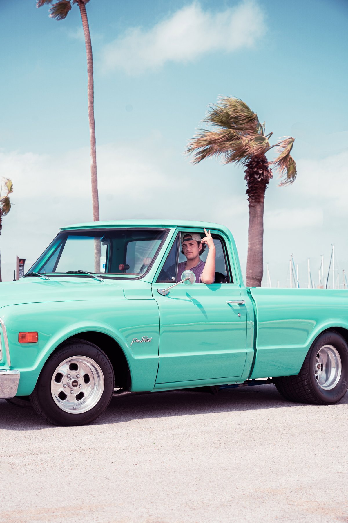 A teal 1968 Chevrolet C10 Pro-Street pickup with chrome rims and a man in the driver's seat.