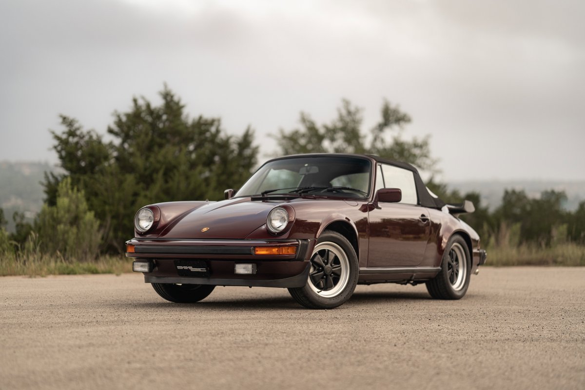 1983 Porsche 911SC Cabriolet in Ruby Red Metallic. Classic black soft top and Fuchs rims.