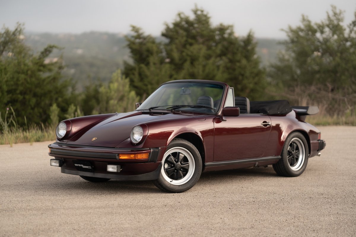 Ruby Red Metallic 1983 Porsche 911SC Cabriolet with black Fuchs rims and whale tail spoiler.