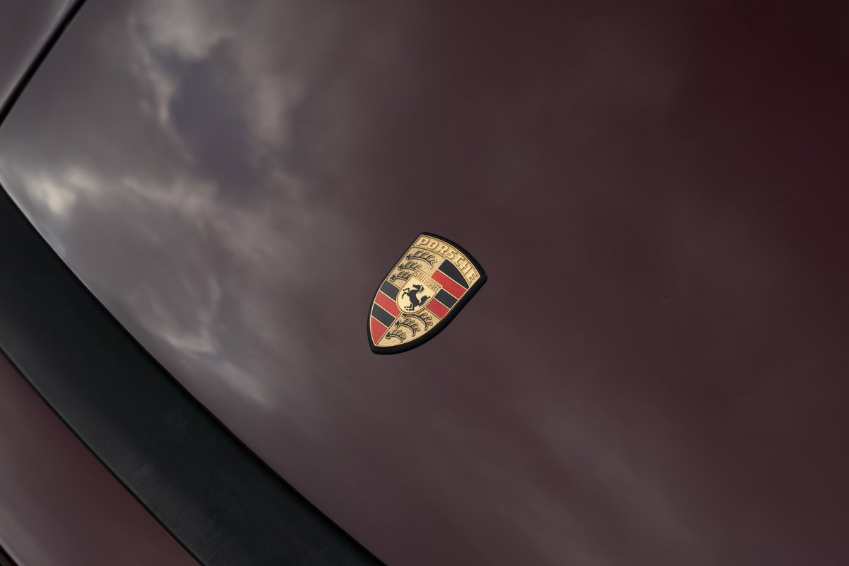 Porsche crest emblem on a ruby red metallic 1983 Porsche 911 SC Cabriolet hood.