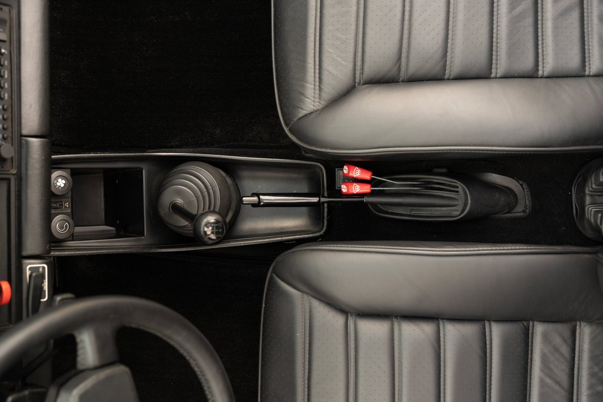Close-up of a 1983 Porsche 911 SC Cabriolet interior, showing a manual shifter and black leather seats.