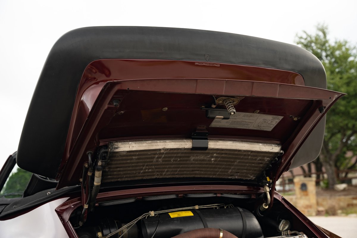 Ruby red 1983 Porsche 911SC Cabriolet with open front trunk showing radiator and condenser.