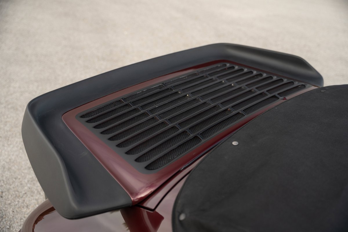 Close-up of a ruby red metallic 1983 Porsche 911 SC Cabriolet rear decklid grille and spoiler.