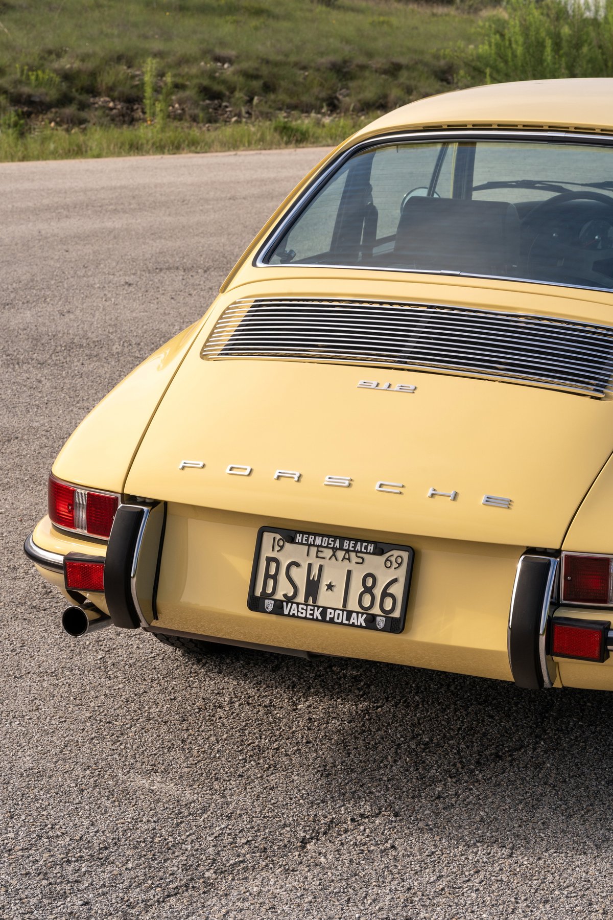 Yellow 1969 Porsche 912 Coupe rear detail with chrome trim and license plate.