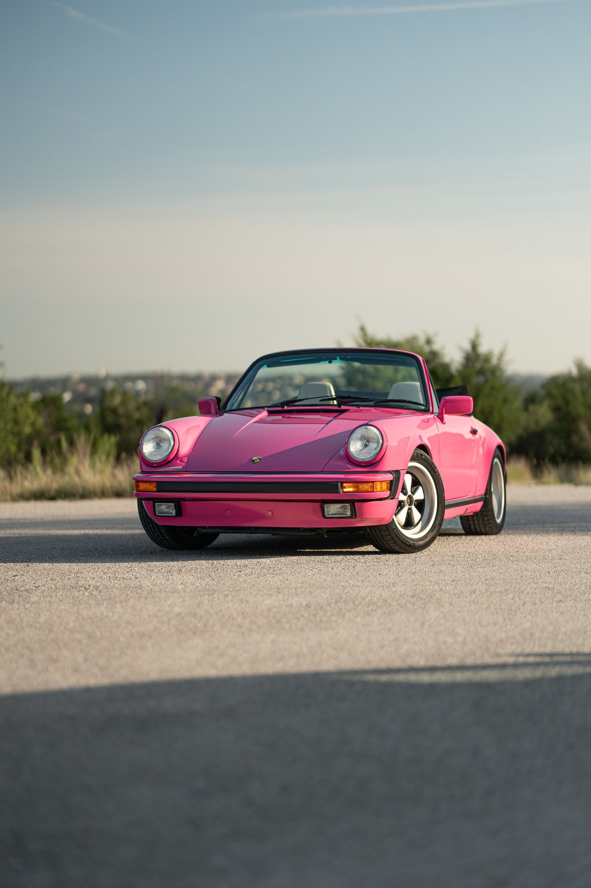 A pink Porsche 911 convertible with Fuchs wheels, captured from the front.