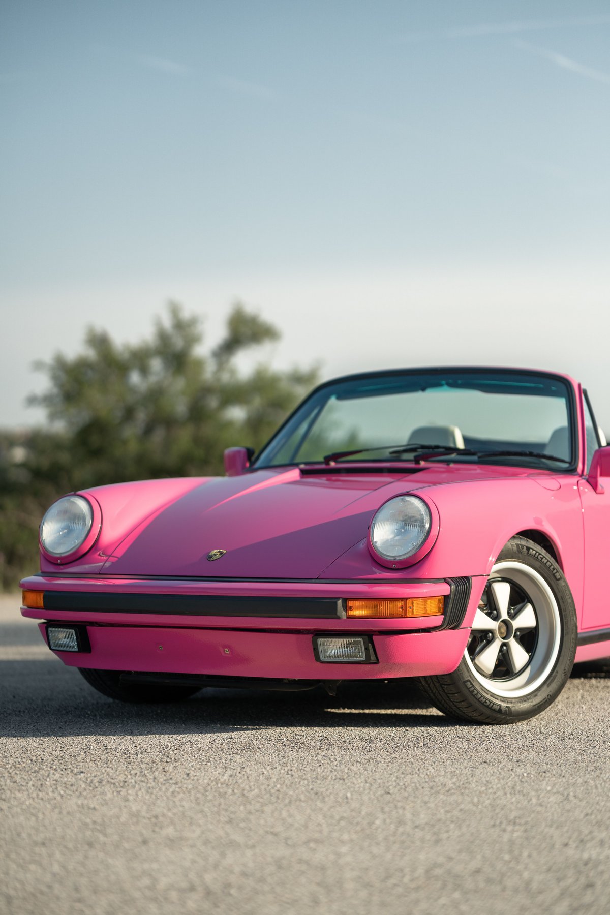 Close-up of a pink Porsche 911 convertible showing front fender, headlamp, and Fuchs rims.