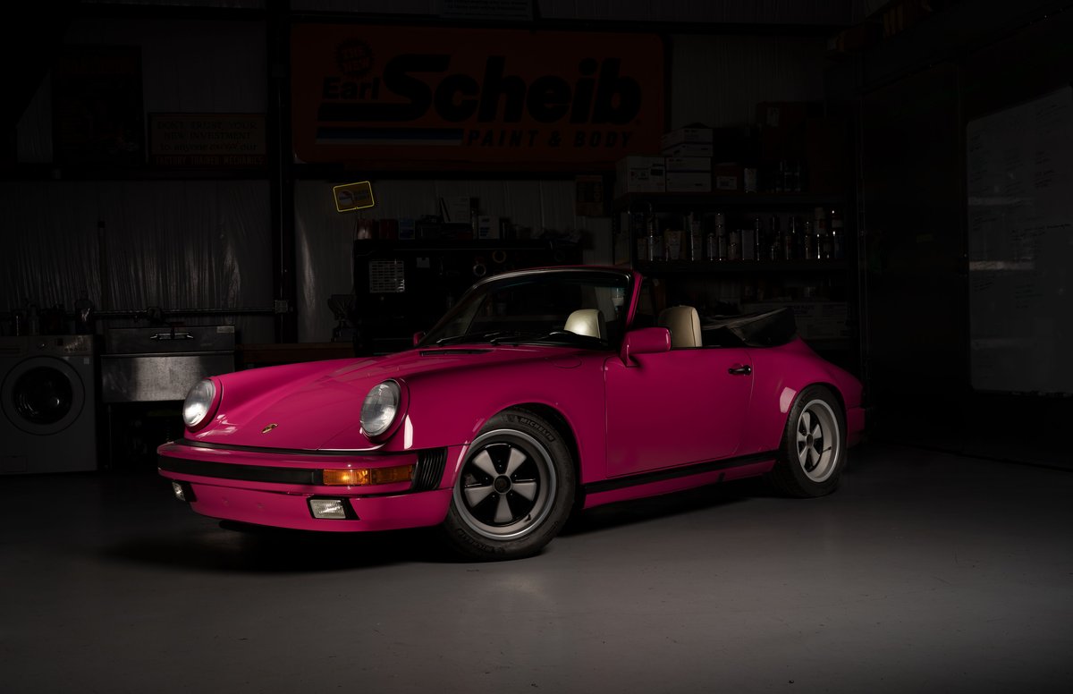 A custom pink Porsche 911 convertible with black trim and Fuchs rims.