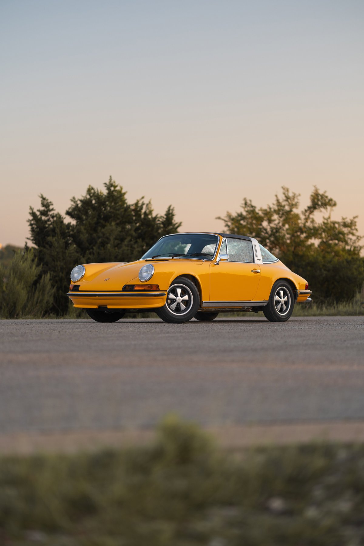 Yellow 1973 Porsche 911S Targa with Fuchs wheels and black Targa top.