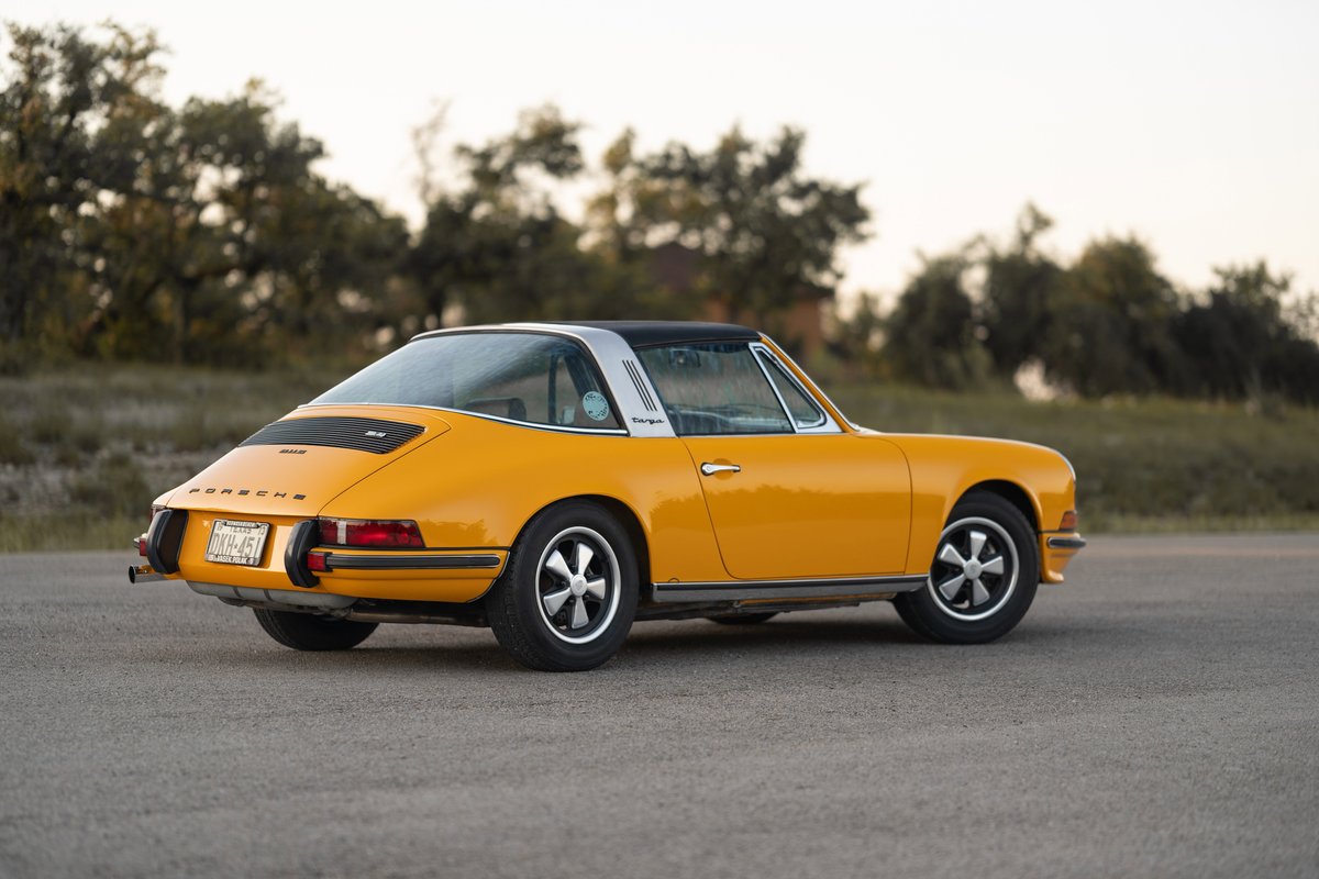 Rear quarter view of a yellow 1973 Porsche 911S Targa with Fuchs rims.