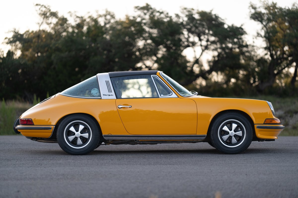 Side profile of a signal yellow 1973 Porsche 911S Targa with Fuchs wheels.