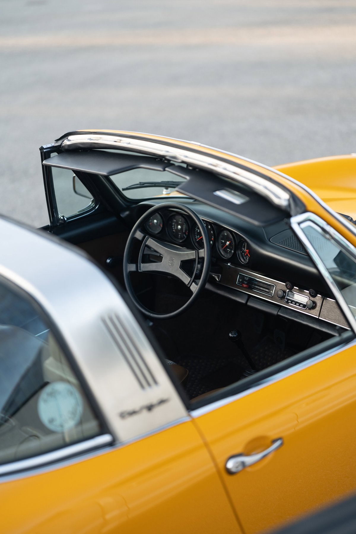 1973 Porsche 911S Targa interior in Signal Yellow. Classic dashboard, steering wheel, and targa trim detail.