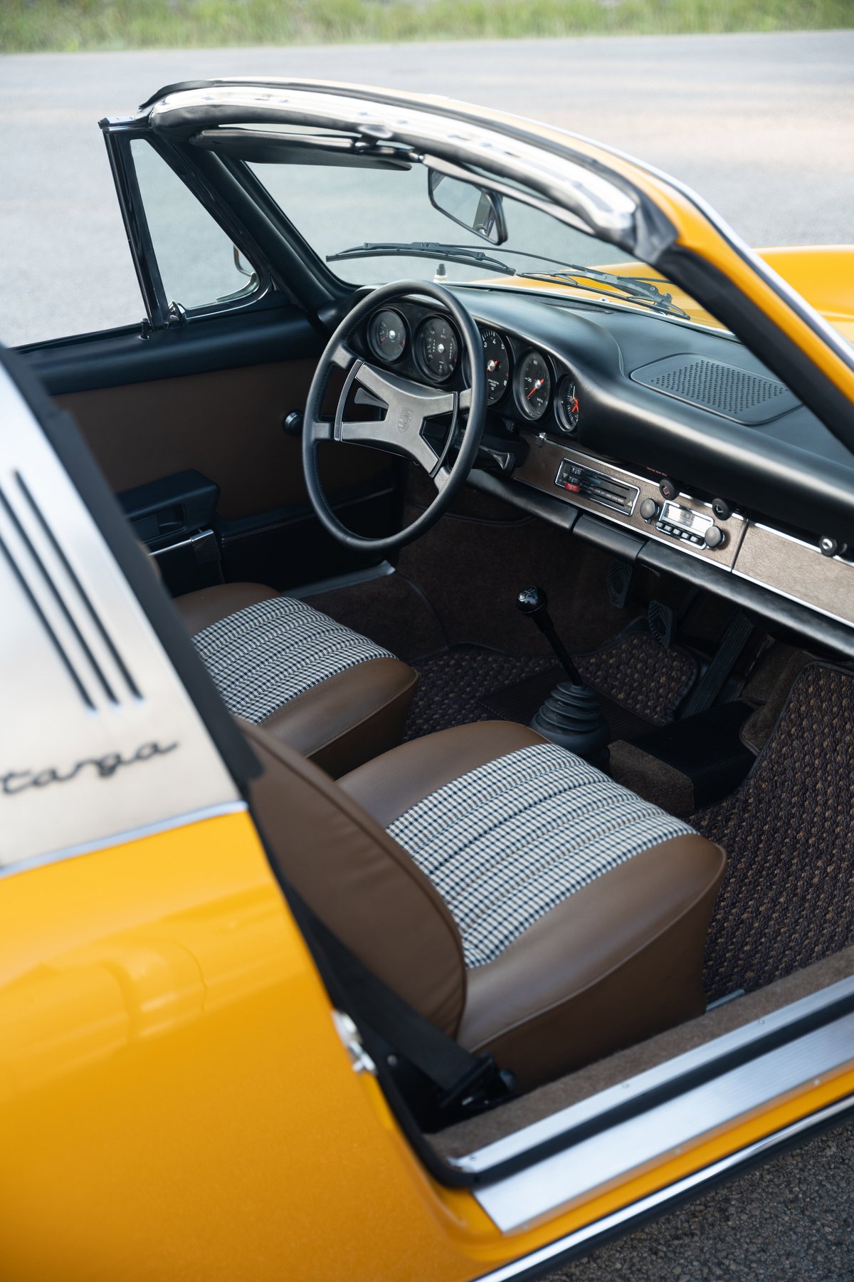 Interior of a yellow 1973 Porsche 911S Targa with houndstooth and brown leather seats.