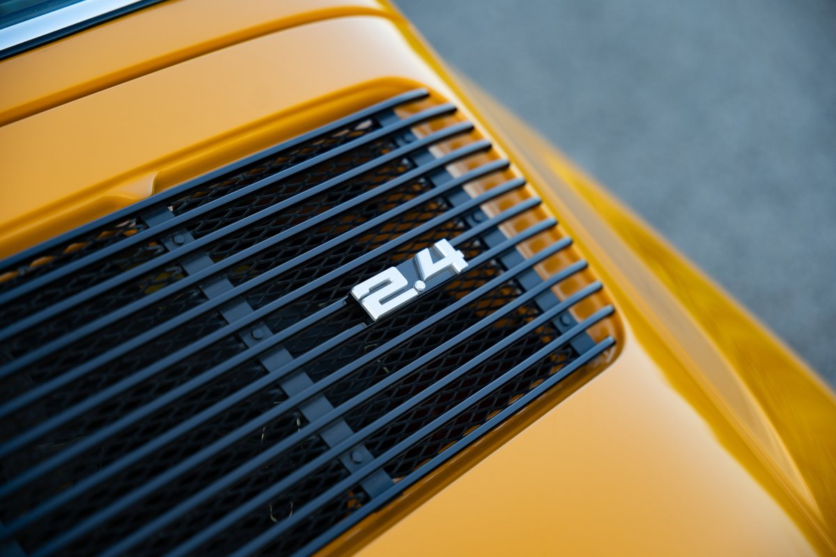 Close-up of a yellow 1973 Porsche 911S Targa's black engine grille with "2.4" badging.